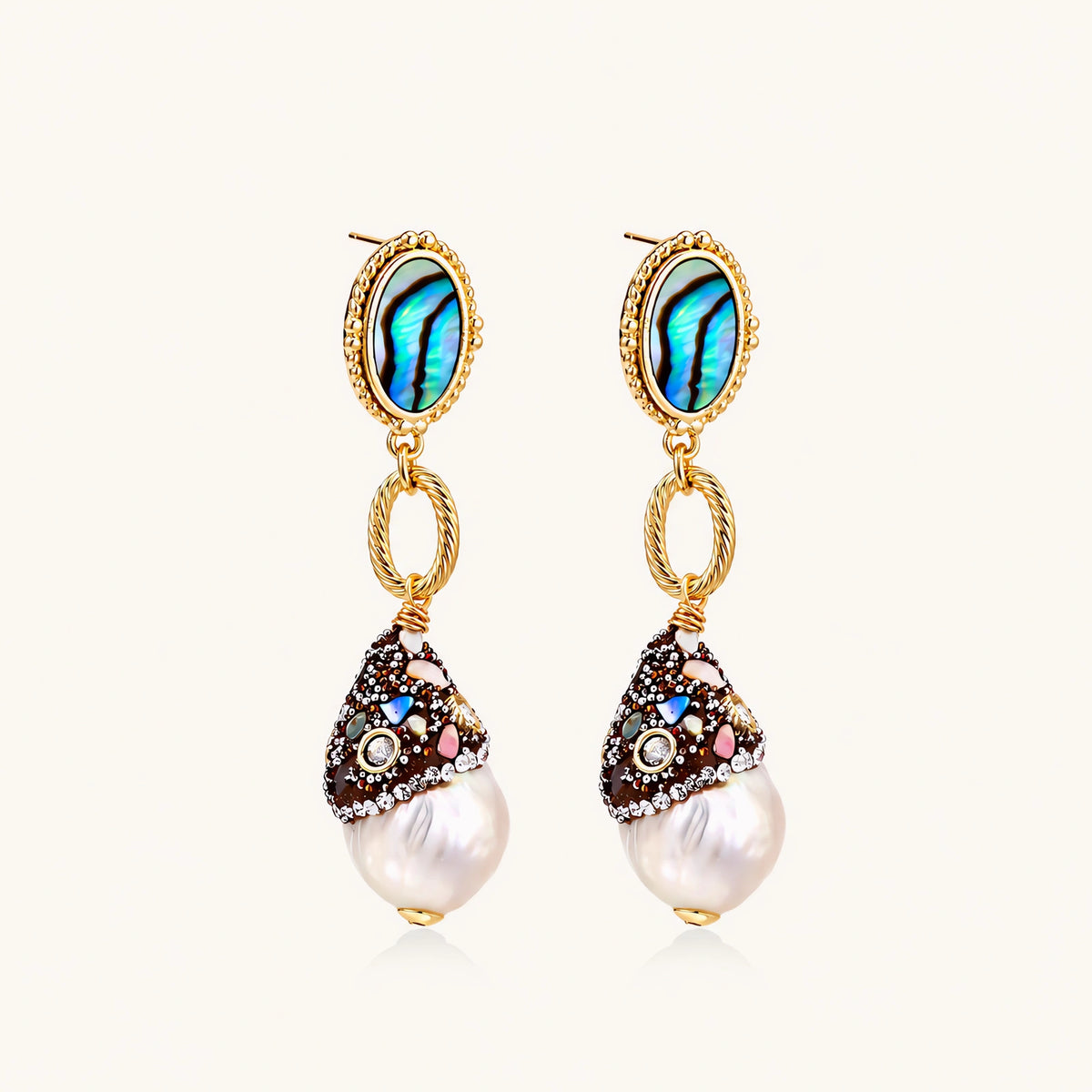 Gold drop earrings with iridescent abalone studs, rope links, jeweled caps and white baroque pearls on cream background