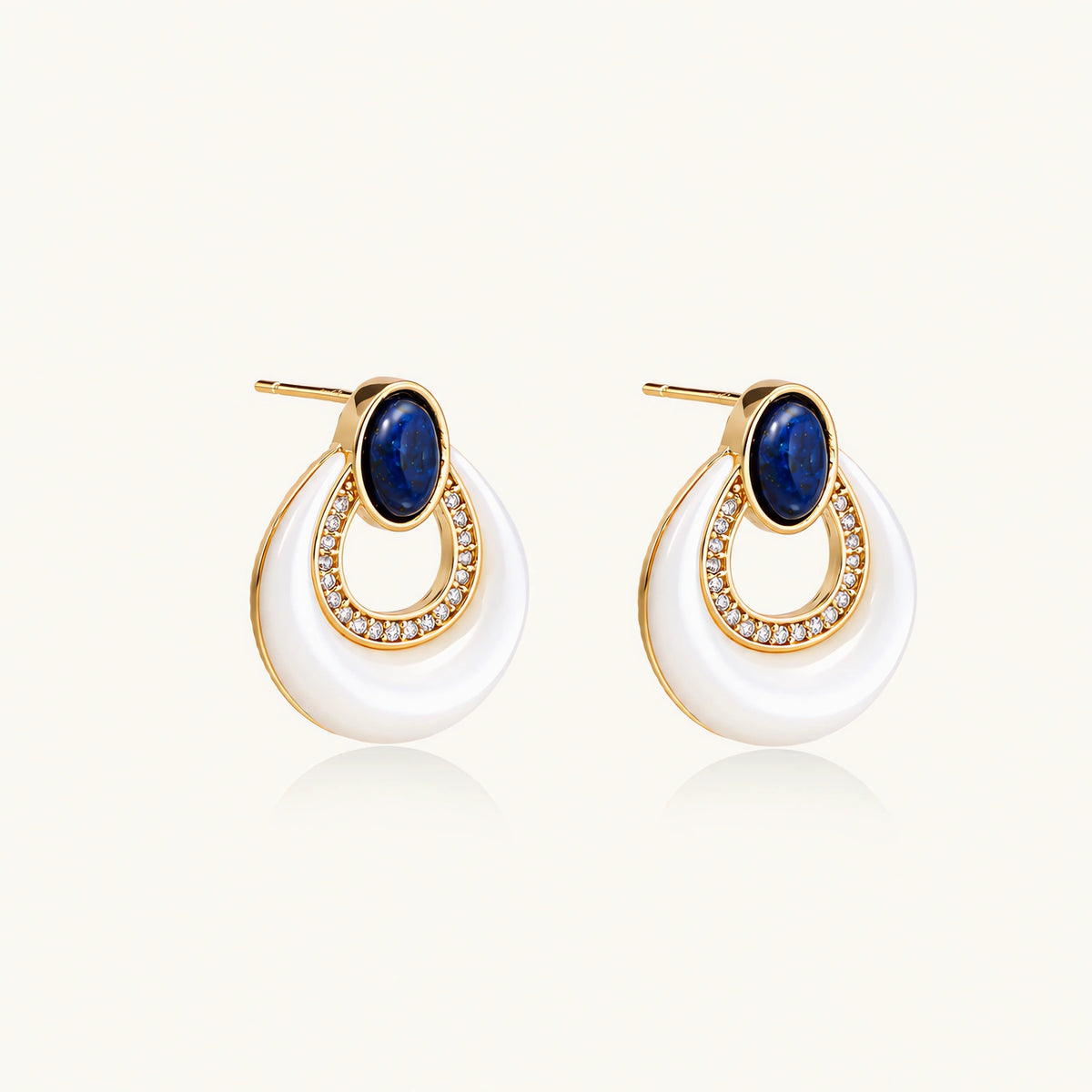 Gold plated stud earrings with an oval lapis lazuli top, CZ-lined teardrop loop and white MOP crescent on a cream background.