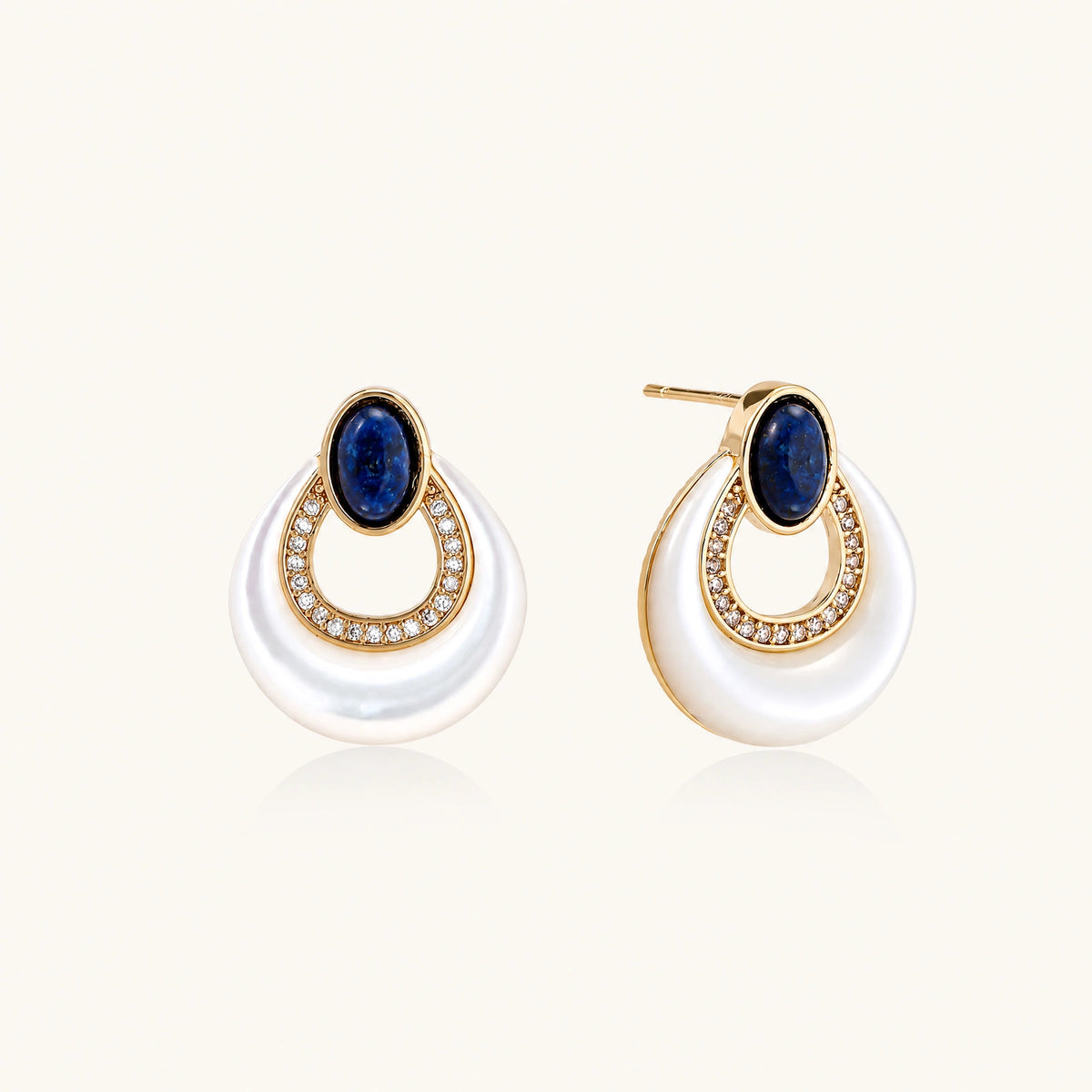 Gold plated stud earrings with an oval lapis lazuli top, CZ-lined teardrop loop and white MOP crescent on a cream background.
