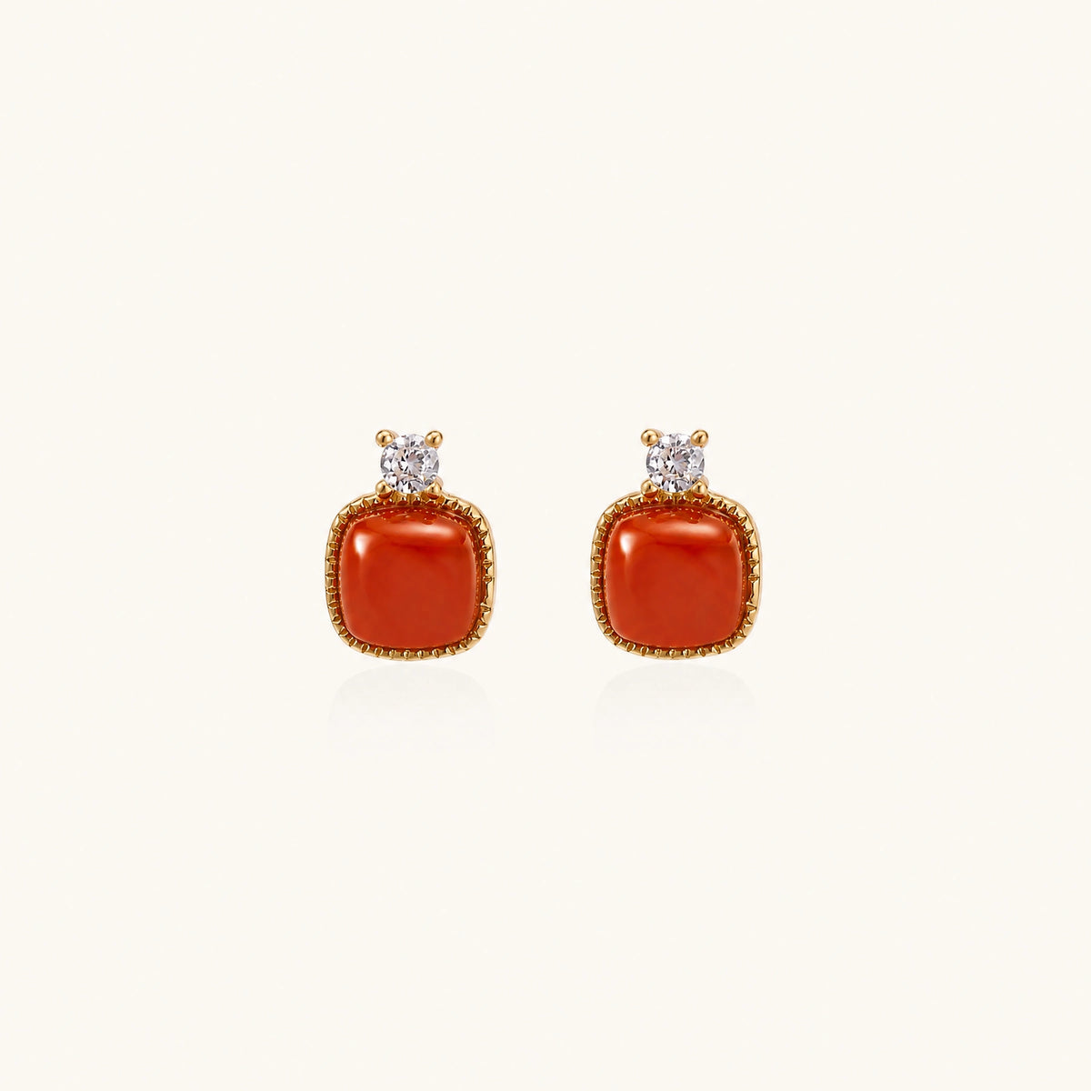 18K gold vermeil stud earrings with cushion-cut red agate stones and sparkling crystal accents on beige background