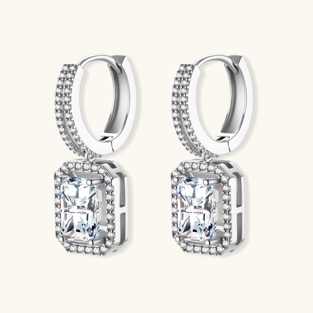 Sterling silver huggie hoops with emerald-cut moissanite drops featuring pavé-set crystals on white background.