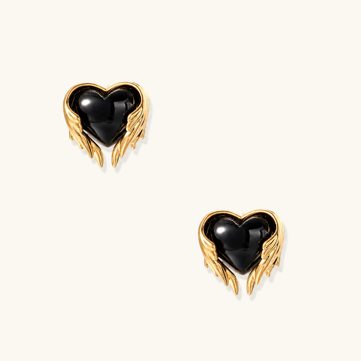Glossy black heart-shaped studs with gold wing accents on cream background, gothic romantic style earrings