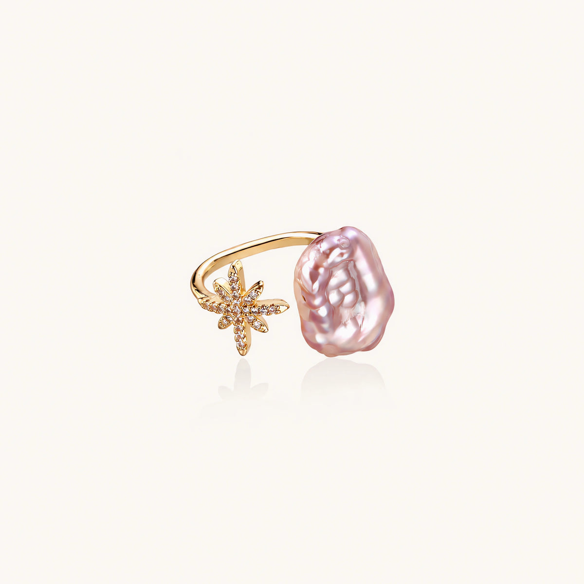 Adjustable gold ring with pink baroque freshwater pearl and crystal-studded star charm on white background