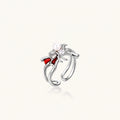Silver-tone spider ring with red drip wings, a white bead and a round zirconia center on an open adjustable band.