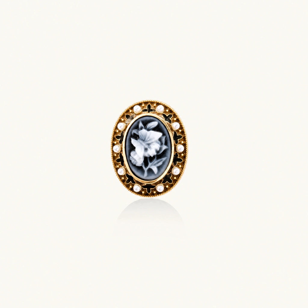 Gold-plated ring with oval blue floral cameo, pearl accents, and black enamel detailing on white background.