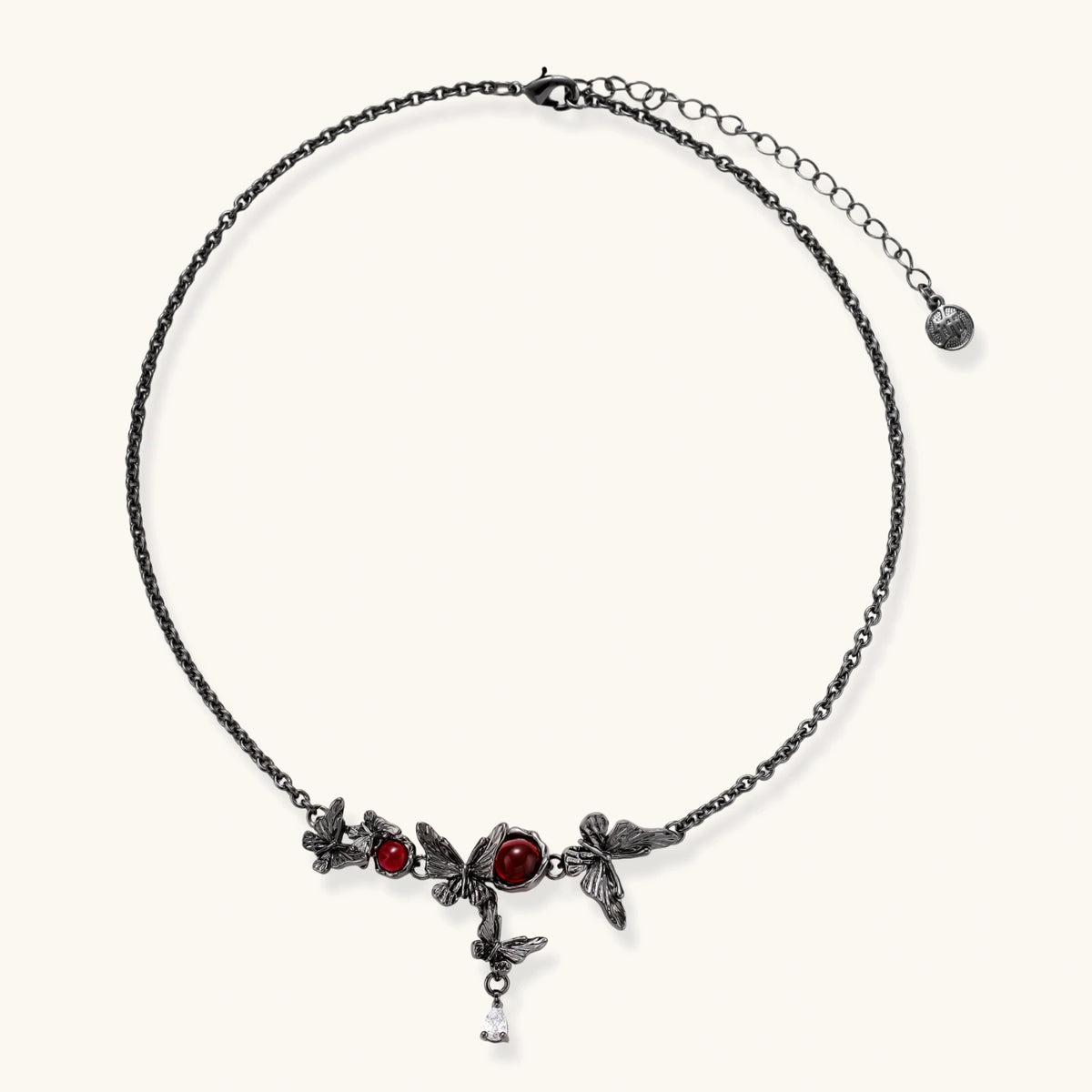 Dark oxidized metal necklace featuring red resin stones set in decorative leaf vine design with crystal drop pendant.