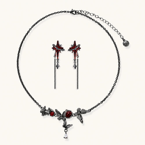 Gothic jewelry set with red resin cross pendants wrapped in dark metal chains on cream background.