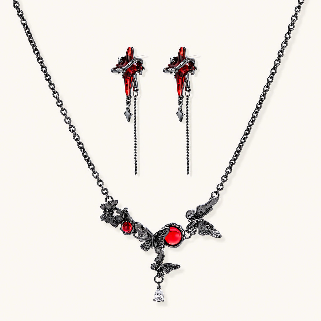 Gothic jewelry set with red resin cross pendants wrapped in dark metal chains on cream background.