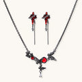 Gothic jewelry set with red resin cross pendants wrapped in dark metal chains on cream background.