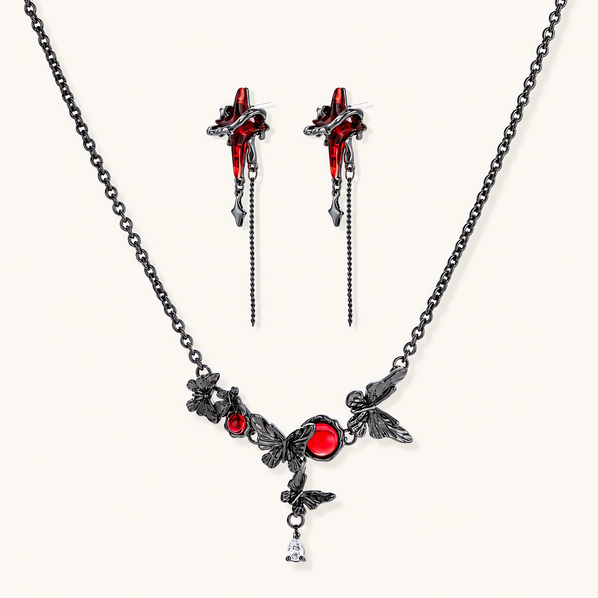 Gothic jewelry set with red resin cross pendants wrapped in dark metal chains on cream background.