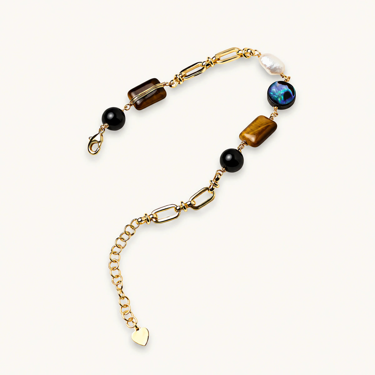 Gold chain bracelet with tiger's eye, obsidian, pearl, and iridescent abalone stones on cream background.