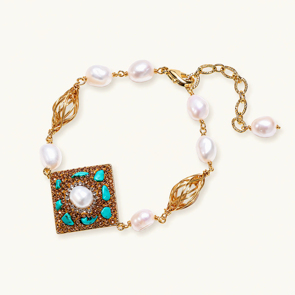 Gold-plated bracelet with baroque centerpiece, turquoise stones, freshwater pearls, and ornate chain links on cream background.