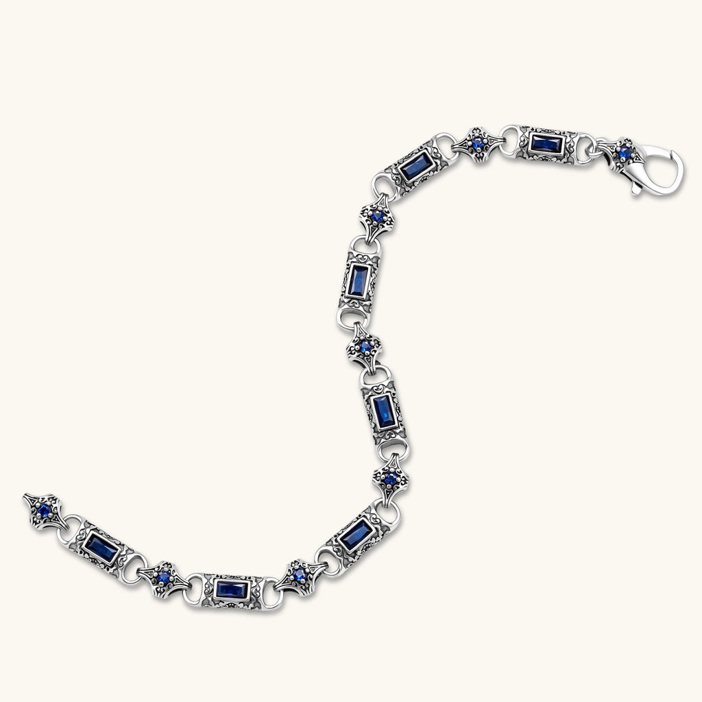 Antique silver plated eco-brass link bracelet with engraved scrollwork, blue baguette cubic zirconia and a lobster clasp.