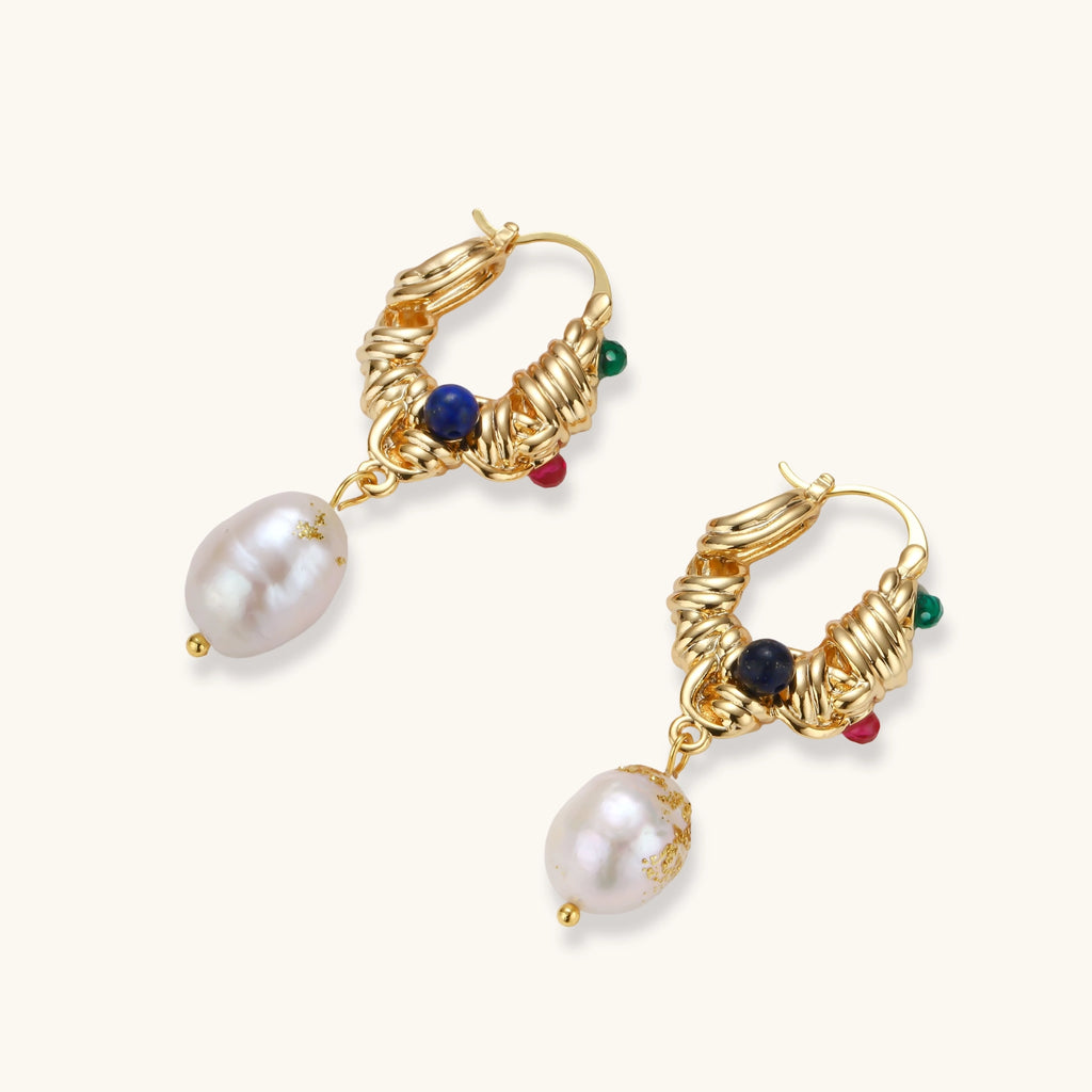 Pair of gold twisted-rope hoop earrings with green, pink and blue beads and baroque freshwater pearl drops on a cream background.