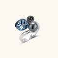 White gold plated eco-brass bypass ring with a large denim-blue cushion stone, a small smoky gray round stone and a dark gray bead.